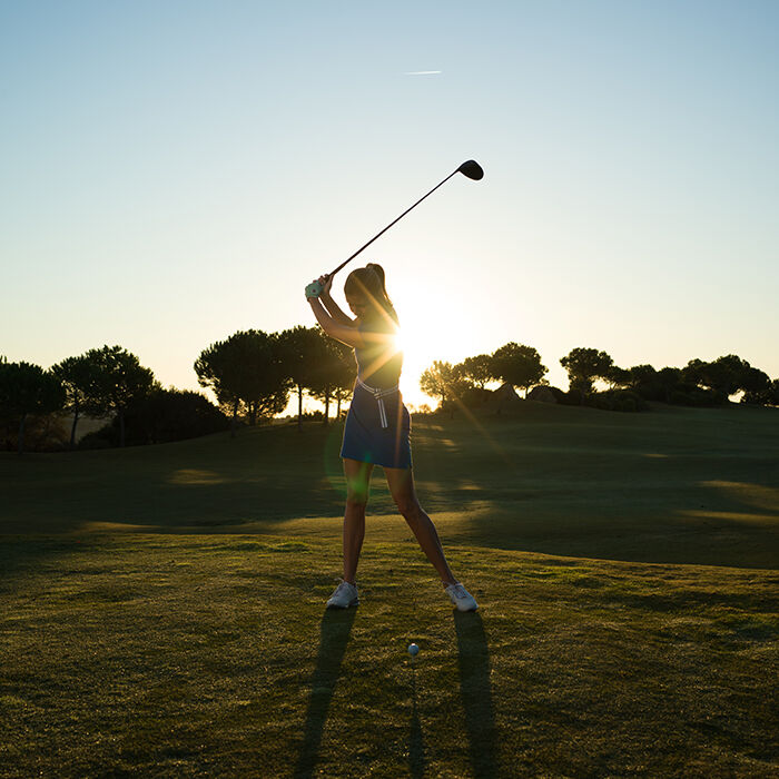 Lady golfing at sunset